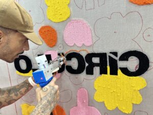 Artista cria painel em tempo real utilizando técnica de tufting na Rio Artes Manuais